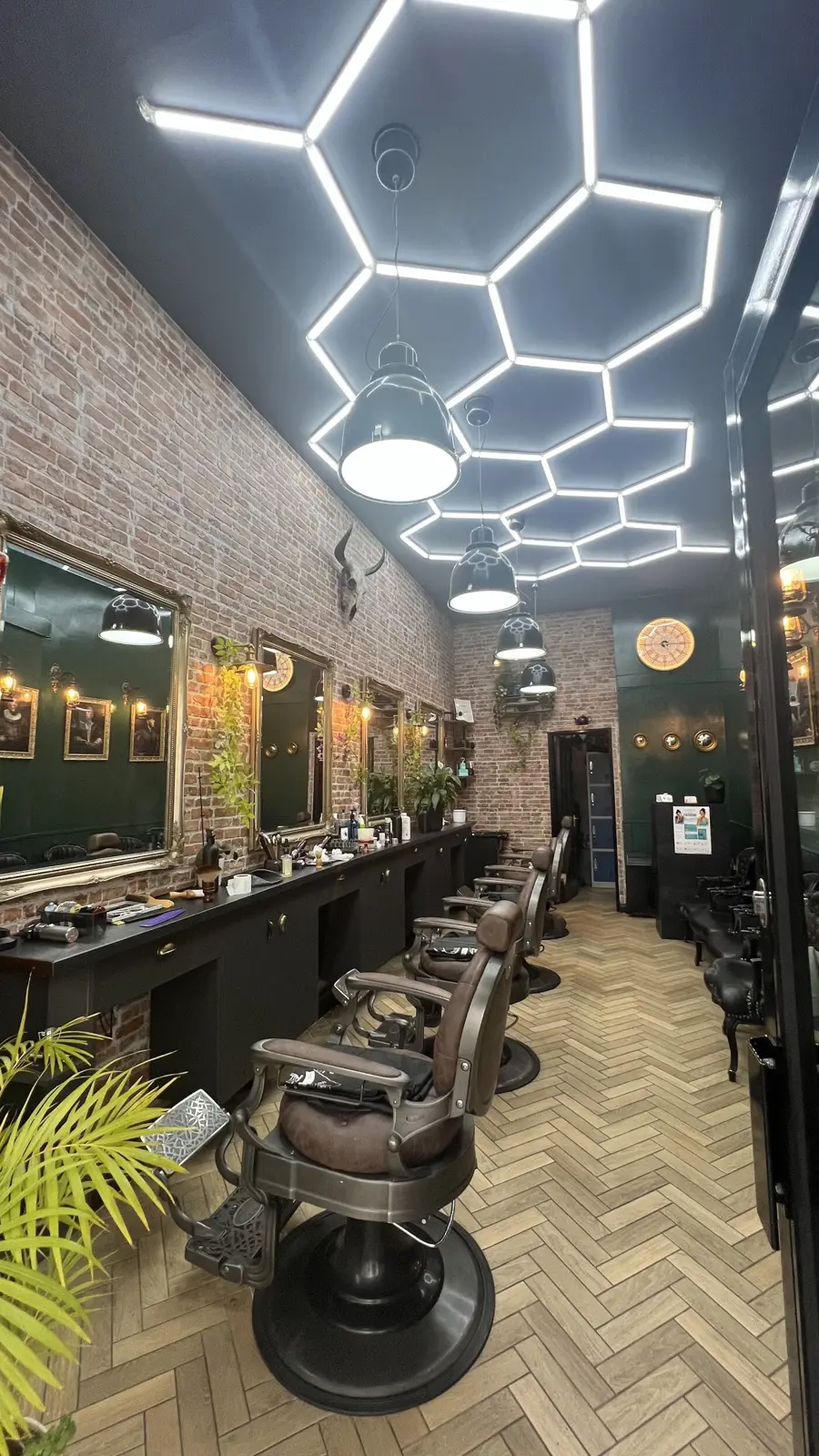 The row of barber chairs facing gilt mirrors along an exposed brick wall